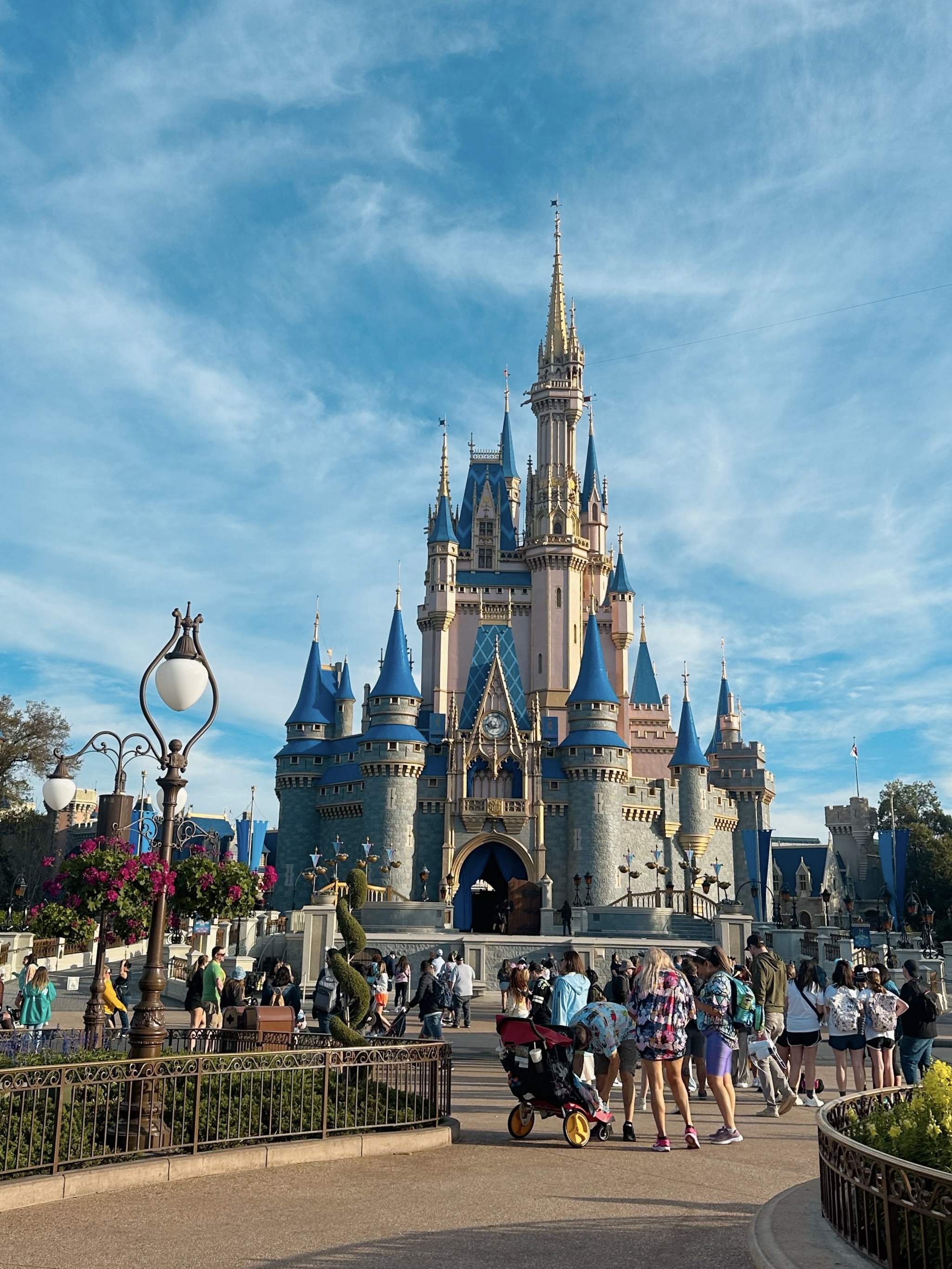 Cinderella Castle at Walt Disney World under a blue sky, with flowers beside the entrance