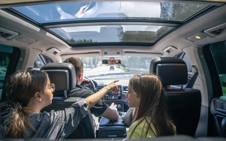 Two young girls buckled into the back seat of a car on a family trip